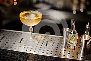 Elegant cocktail glass filled with alcoholic drink on the bar counter