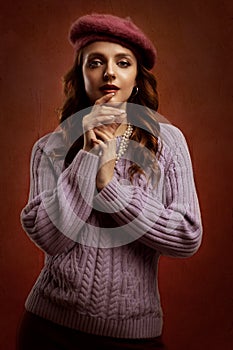 An elegant, confident, curly-haired young woman in a knitted beret and jacket.