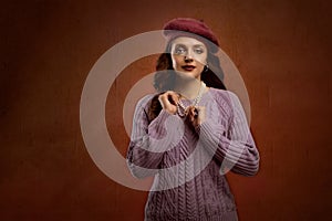 An elegant, confident, curly-haired young woman in a knitted beret and jacket.