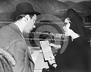 Elegant couple at a horse race looking at a program