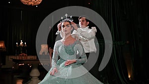 Elegant couple performing a dance, woman in a sparkling dress and tiara, man in a white shirt, dark backdrop