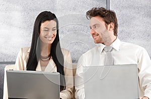 Elegant couple sitting on sofa using laptop