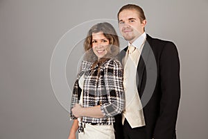 Elegant couple smiling for the camera while embracing. On grey background.