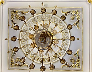 Elegant crystal chandelier hanging on the gilded gold ceiling. Luxury living room ceiling decoration