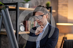 Elegant dark-haired woman standing near flipchart and looking thoughful