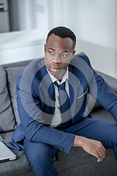 Elegant dark-skinned man sitting and looking anticipated