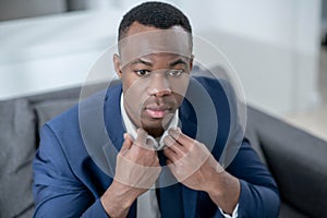 Elegant dark-skinned man sitting and looking anticipated