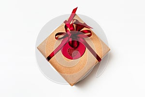 Elegant design of present gift box wrapped in brown craft paper with red ribbon and red tag
