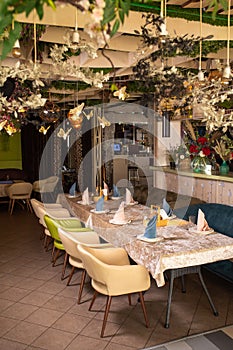 Elegant dining area with greenery, long table with crystal glasses and napkins.