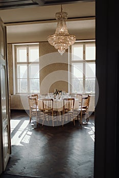 Elegant dining room with a beautifully set table, wooden flooring, and a stunning chandelier.