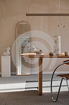 Elegant dining room interior composition with wooden dining table, armchair and design home decorations. Modern home staging.