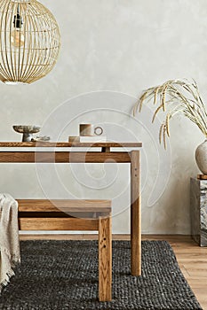 Elegant dining room interior composition with wooden dining table, bench and design home decorations and personal accessories.