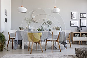 Elegant dining room interior with a laid table, chairs, mirror on a wall and lamps