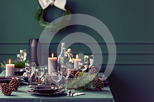 Elegant dining room table with wine glasses, plates and candles set for christmas dinner