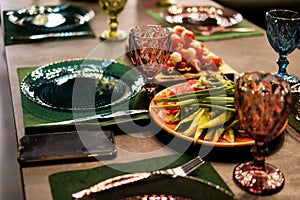 Elegant dining setup with vintage blue glassware; a plate of fresh vegetables adds a touch of health consciousness