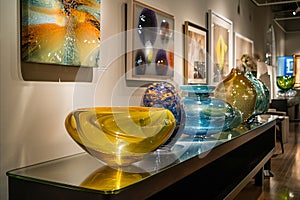 Elegant display of intricate glasswork in a gallery, pieces illuminated against a shiny floor