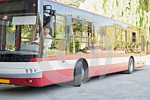 Elegant driver sitting in shuttle bus, working in city.