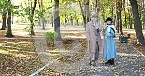 Elegant, elderly married couple talking during a walk in sunny, autumn park