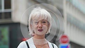 Elegant elderly woman 65-70 years old walking in the city on a summer day.