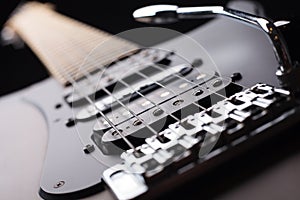 Elegant electric guitar on black background close up point of view from bridge