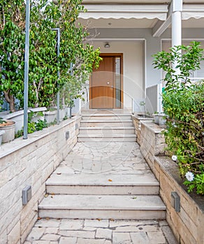 An elegant family home entrance marble covered coridor to the natural wood door, plenty of plants.