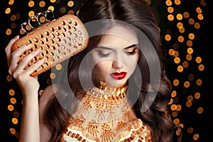 Elegant fashion brunette woman in gold. Wavy hair style. Red lip