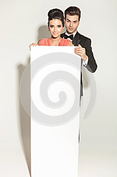 Elegant fashion couple holding a white empty board