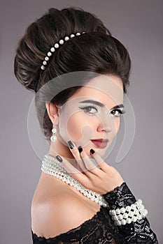 Elegant fashion jewelry woman portrait. Brunette lady with makeup and hairstyle, pearls accessories set posing isolated on studio