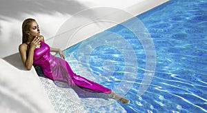 Elegant fashion model in amazing dress is standing in pool and sensualy posing. Elegance. Chic woman in amazing shiny dress in