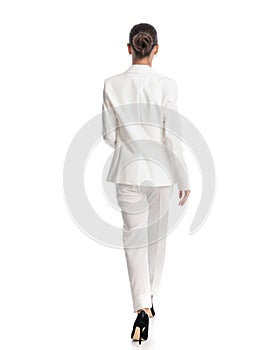 elegant fashion model with bun hair in white suit walking