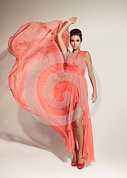 Elegant fashion woman fluttering her coral dress