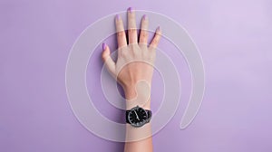 Elegant female hand with fashionable wristwatch on a purple background