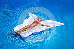 Elegant female model in stylish bikini is lying on a butterfly-shaped mattress in the pool. Sexy woman in amazing sequin bikini is