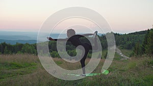 Elegant flexible sporty fit african woman standing in dancer yoga pose in mountains at daybreak