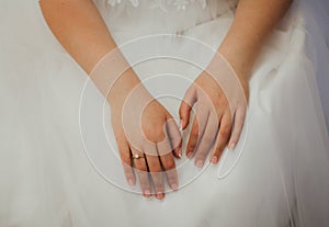 Elegant french manicure for wedding day. Bride is holding her hands with nice nails and engagement ring on white tulle puffy dress