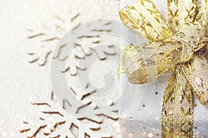 Elegant gift box wrapped in sliver paper with golden ribbon with bow on snowy background snow flakes relieves. Christmas New Years