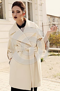 Elegant girl with dark hair wearing luxurious beige coat