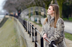 Elegant girl in fur coat walking alone in winter city alley