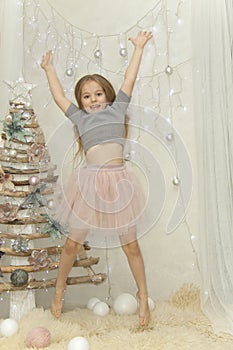 Elegant girl jumps up near a fur-tree