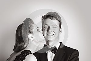 Elegant girl kisses a happy young man on the cheek