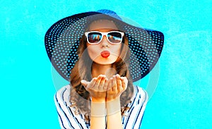 Elegant girl with red lips is sends an air kiss in straw summer