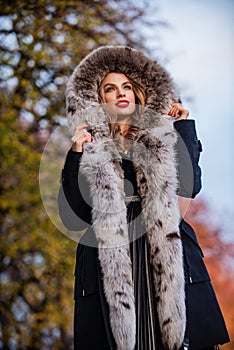 Elegant girl walk in autumn park. Fur garments. Really warm and cozy. Expensive clothes. Luxury segment brand. Luxury