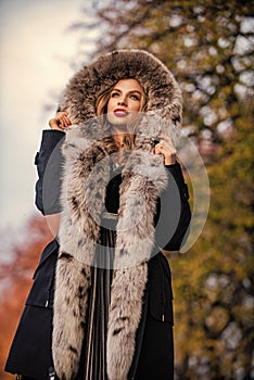 Elegant girl walk in autumn park. Fur garments. Really warm and cozy. Expensive clothes. Luxury segment brand. Luxury