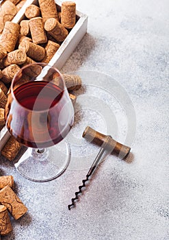 Elegant glass of red wine with box of corks and opener on stone kitchen table background