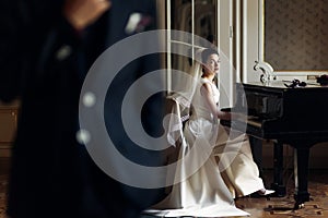 Elegant gorgeous bride playing the fortepiano in rich old room a photo