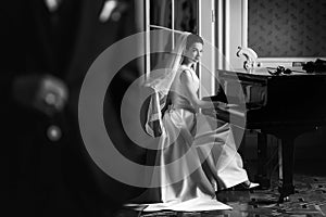 Elegant gorgeous bride playing the fortepiano in rich old room a photo