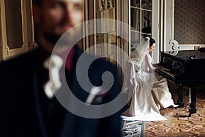 elegant gorgeous bride playing the fortepiano and stylish handsome groom posing in rich old room. sensual look. unusual luxury we photo