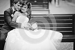 Elegant gorgeous happy bride and groom sitting on a bench on the