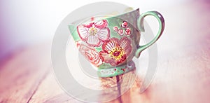 Elegant green floral mug isolated on wooden table
