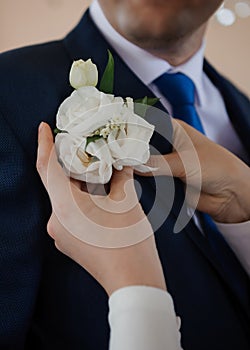 Elegant Groom Preparation: Pinning a White Floral Boutonniere photo